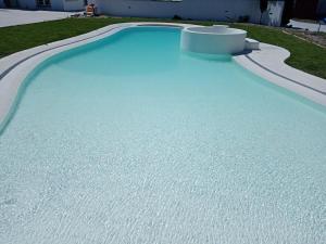 a swimming pool with blue water in a yard at Moradia Vila Rosa in Ponte de Vagos