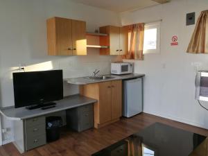 a kitchen with a desk with a television and a microwave at Star Motel in Morden