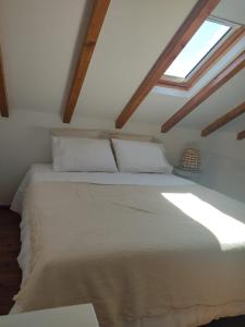 a bedroom with a large white bed with a window at Villa Vista in Sesimbra