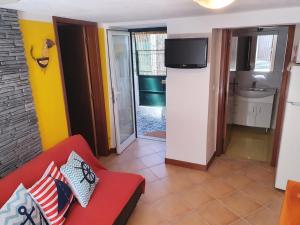 a living room with a red couch and a tv at Casinha dos Figueirais in Góis