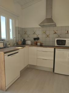 cocina con armarios blancos y microondas en Villa Vista en Sesimbra