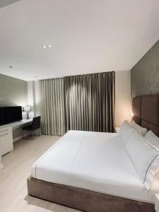 a bedroom with a large white bed and a desk at Hotel Oresti Center in Tirana