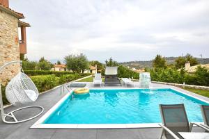 una piscina en un patio trasero con sillas y una piscina en Earthy Boutique Luxurious House -Marble Luxury House en Paliouri