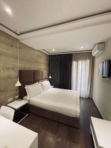 1 dormitorio con 1 cama grande con sábanas blancas en Hotel Oresti Center, en Tirana