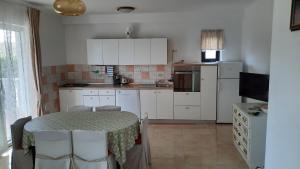 a kitchen with a table and a kitchen with white cabinets at Apartments Ankica - pool & garden in Kampor