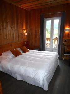a large white bed in a room with a window at Hôtel des Skieurs in Le Sappey-en-Chartreuse