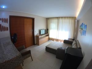 a living room with a couch and a television at [Kariri 215] 46m², pé na areia, varanda vista mar! in Cumbuco