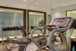 un gimnasio con 2 máquinas de cardio y espejos en The Sahil Hotel en Bombay