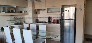 uma cozinha com uma mesa de vidro e um frigorífico de aço inoxidável em Departamento Laguna Bahía 808 Velero em Algarrobo