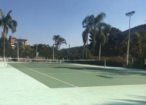 una pista de tenis con palmeras al fondo en Apart-Hotel Cavalinho Branco (311 e 409 ), en Águas de Lindóia