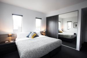 a hotel room with two beds and a mirror at Tyrian Serviced Apartments Fitzroy in Melbourne
