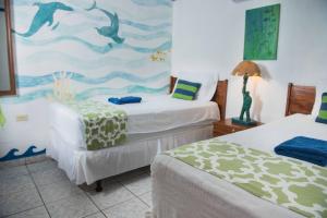 a bedroom with two beds and a painting of dolphins at Olas Permanentes El Zonte in El Zonte
