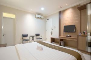a hotel room with a bed and a flat screen tv at Life Emerald Hotel Surabaya in Surabaya