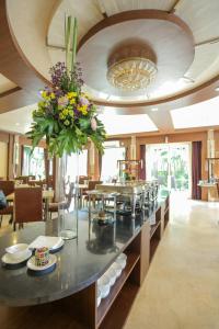 Country Heritage Hotel في سورابايا: غرفة طعام مع طاولة مع إناء من الزهور