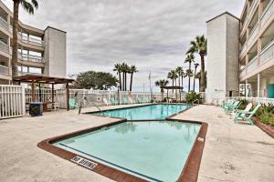 a swimming pool with chairs and a building at Oceanfront Corpus Christi Escape with Community Pool in Corpus Christi