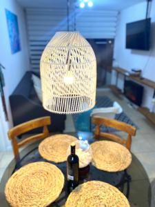 una mesa con tres mesas con una lámpara y una botella de vino en Departamento vista al mar, en El Tabo