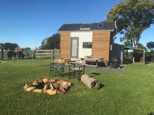 a tiny house with a pile of logs in the grass at Tiny Home … BIG Views in Kurrajong