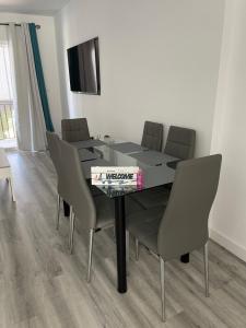 uma sala de jantar com uma mesa com cadeiras e uma televisão em Apartamento BellaThalía em Ayamonte