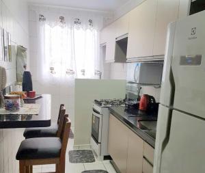 a white kitchen with a stove and a refrigerator at Apartamento TOP CLIMATIZADO em CRICIÚMA-SC - ótimo CUSTO-BENEFÍCIO - Cozinha completa - Cama Box - WiFI - Smart TV - Apps YouTube - NetFlix - Prime Vídeo - Garagem coberta - Portaria Digital 24h - Lugar sossegado e arborizado - Acomoda até 5 pessoas in Criciúma