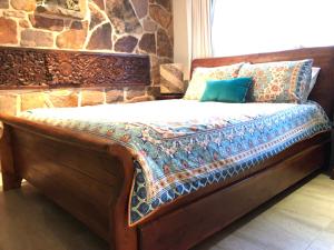 a wooden bed in a room with a stone wall at Bali at the Bay in Nelson Bay