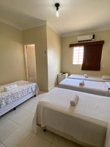a bedroom with two beds and a window at Hotel California in Goiânia