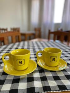 two yellow cups and saucers sitting on a table at Hotel California in Goiânia