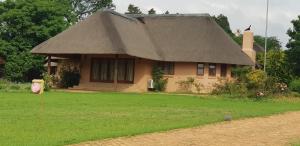 a small house with a thatched roof and a yard at Impangele Lodge in Muldersdrift
