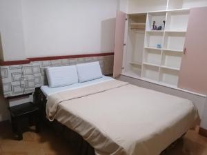 a small bedroom with two beds and a shelf at Manora Apartment in Talisay