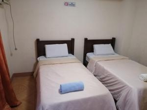 two beds in a room with a blue pillow on them at Manora Apartment in Talisay