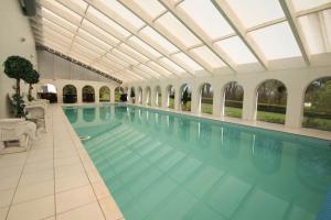 une grande piscine avec un plafond en verre dans l'établissement Kokkedal Slotshotel, à Brovst