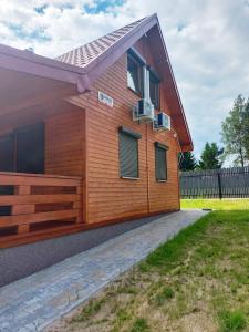 a house with a wooden facade with a yard at Dom NARIE na Mazurach nad Jeziorem Narie in Bogaczewo