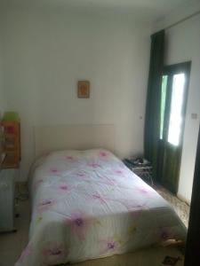 ein Schlafzimmer mit einem Bett mit rosa Blumen drauf in der Unterkunft House with Wala Garden in Mahdia