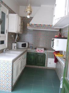 małą kuchnię z zielonymi szafkami i zieloną podłogą w obiekcie House with Wala Garden w mieście Mahdia