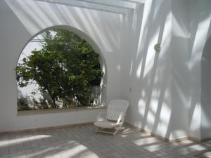 House with Wala Garden في المهدية: كرسي أبيض جالس على شرفة مع نافذة