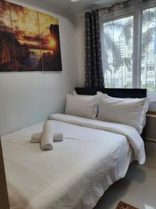 a bedroom with a large white bed with two windows at Vangie's Place at SEA RESIDENCES in Manila