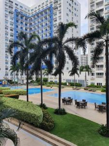 a courtyard with tables and palm trees in a city at Vangie's Place at SEA RESIDENCES in Manila