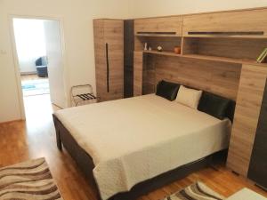 ハイドゥソボスローにあるMatilda Apartmanのベッドルーム1室(大型ベッド1台、木製ヘッドボード付)