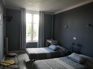 a bedroom with two beds and a window at Hotel du Grand Monarque in Varennes-en-Argonne