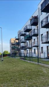 a large apartment building with balconies and a grass field at Apartament Platinum Park in Stargard