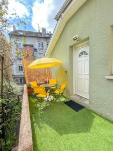 a patio with a table and chairs and an umbrella at Maisonnette Le Faubourg - CENTRE VILLE, TERRASSE ET NETFLIX in Belfort