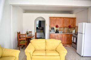 a living room with a yellow couch and a kitchen at Green Castle Apartment#3 in City of Roseau in Roseau