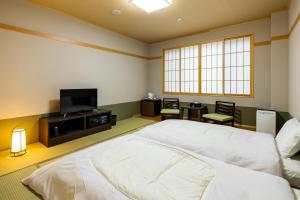 a bedroom with a bed and a flat screen tv at Fujikawaguchiko Resort Hotel in Fujikawaguchiko