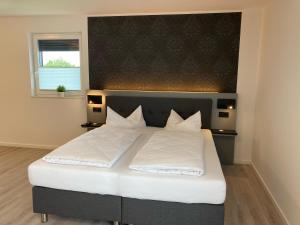 ein Bett mit weißen Laken und Kissen in einem Schlafzimmer in der Unterkunft CAP1 Boardinghouse in Baesweiler
