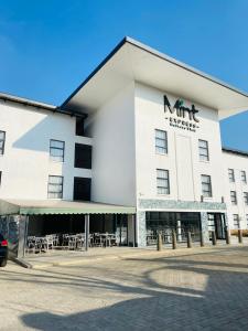 a large white building with tables and chairs at MINT Express Melrose View in Johannesburg