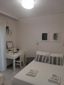 a white bedroom with a bed and a desk at Luxury Townhouse in Larisa