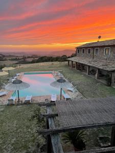 a pool with chairs and umbrellas in front of a house at Le Murelle Country Resort in Manciano