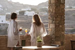 two women standing on a balcony looking out at the city at Mr & Mrs White Mykonos in Platis Yialos Mykonos