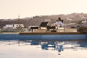 a woman sitting at a piano next to a pool at Mr & Mrs White Mykonos in Platis Gialos