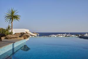 a swimming pool with a palm tree next to a resort at Mr & Mrs White Mykonos in Platis Gialos