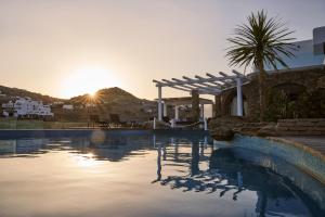 a swimming pool with the sunset in the background at Mr & Mrs White Mykonos in Platis Gialos